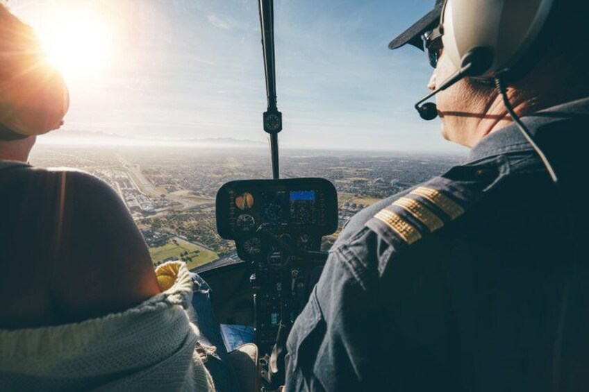 A helicopter cockpit with a pilot and a passenger. 1