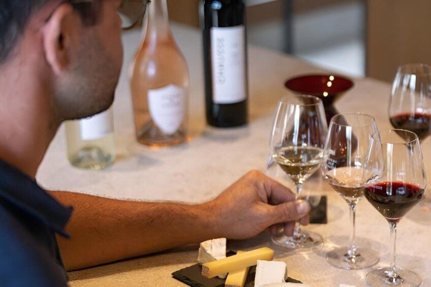 A person tasting wine with glasses and bottles on a table. 4