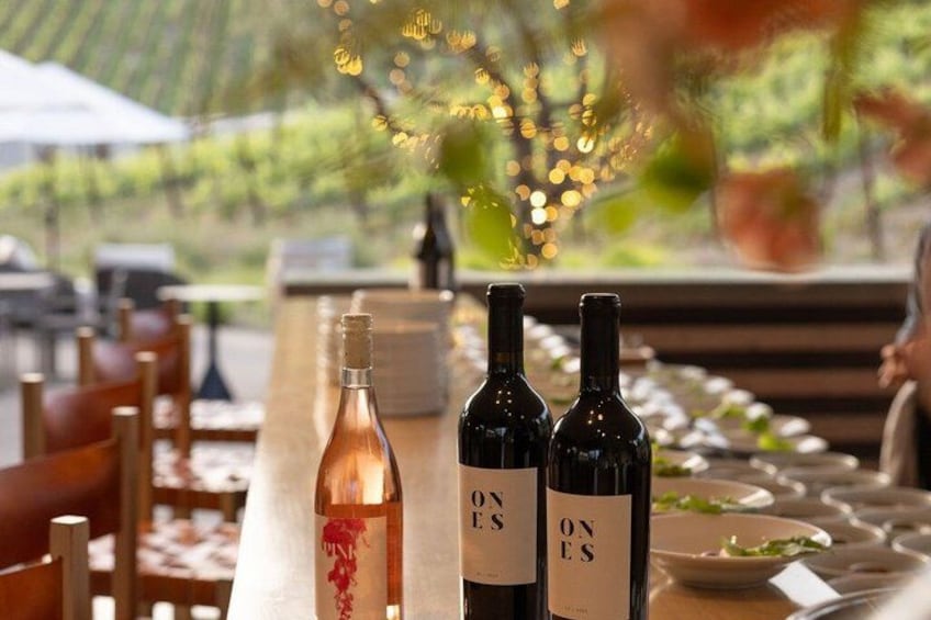 A table with bottles of wine, a candle, and a vase with flowers. 1