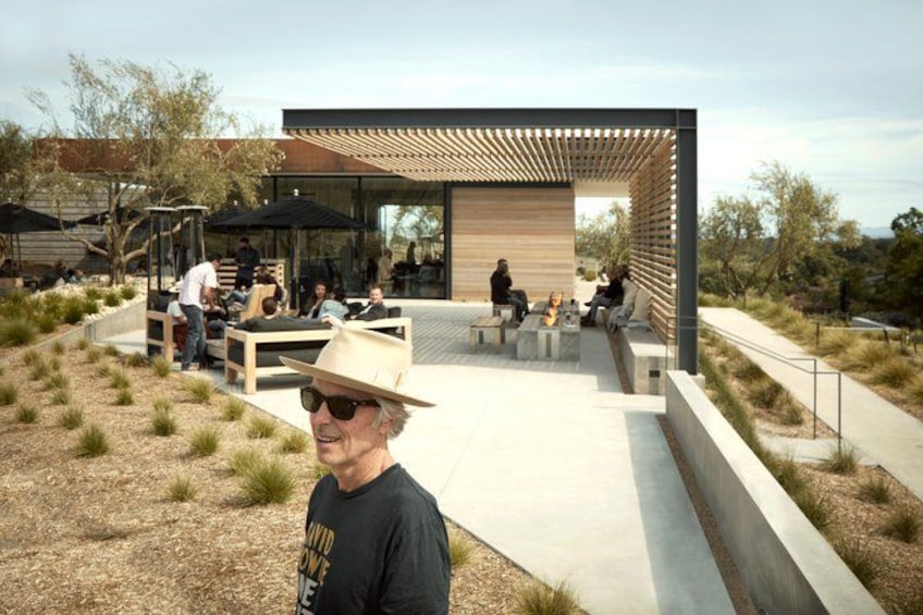 An outdoor seating area with people, a modern building, and a landscaped garden. 2
