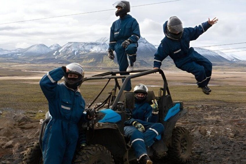 Four people in blue jumpsuits and helmets on a vehicle in a mountainous landscape. 3