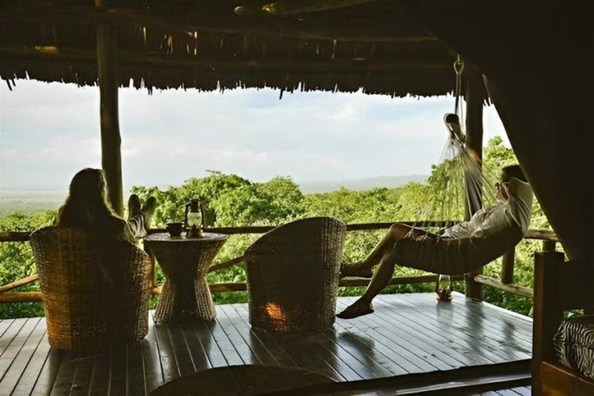 A wooden deck with wicker chairs and a hammock, overlooking a lush landscape. 5