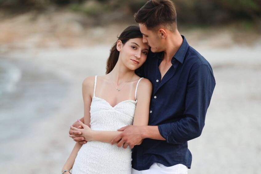A couple embracing on a sandy beach with ocean in the background. 2