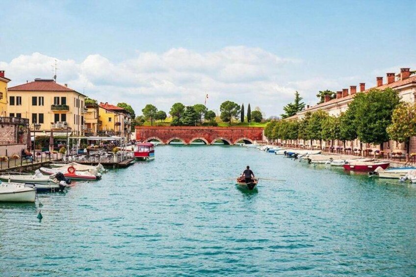 A canal with boats, a bridge, and buildings along the banks. 3