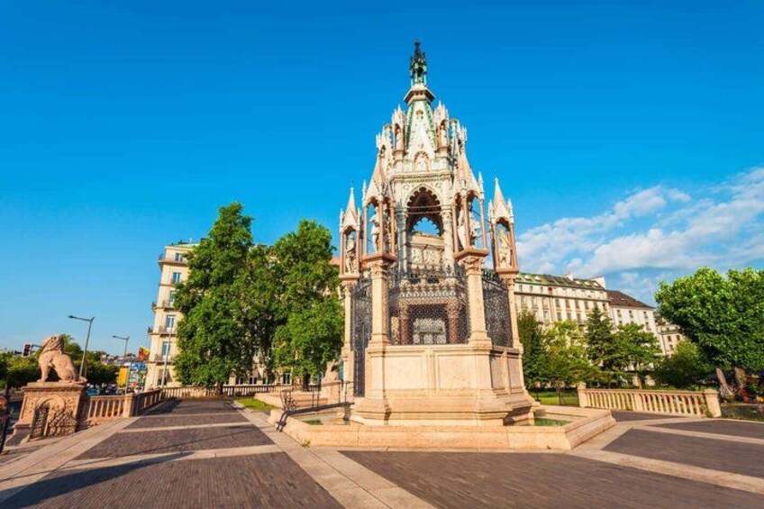 A historic building with intricate architecture, a statue, and a clear blue sky. 2