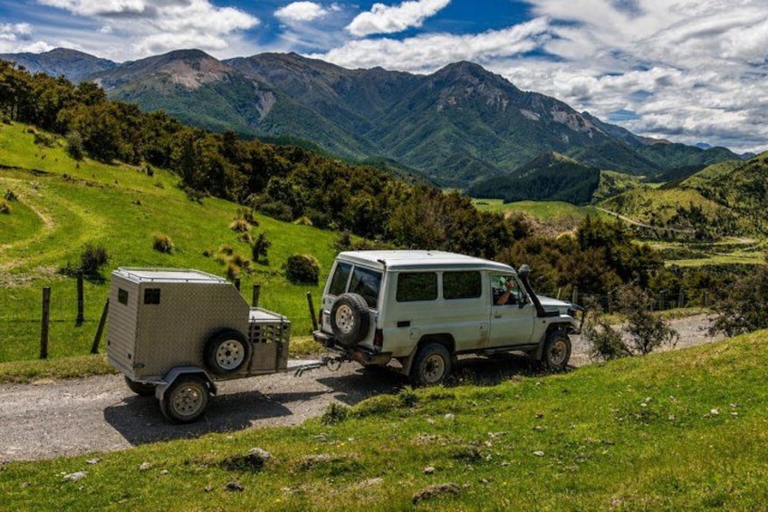 A white SUV with a camper trailer on a dirt road in a mountainous area. 4