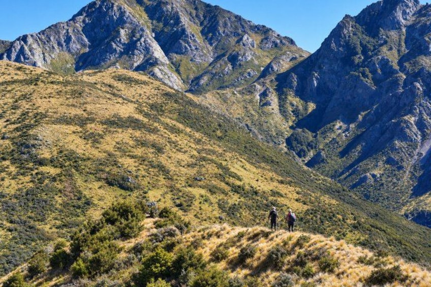 A mountainous landscape with hikers on a trail. 1