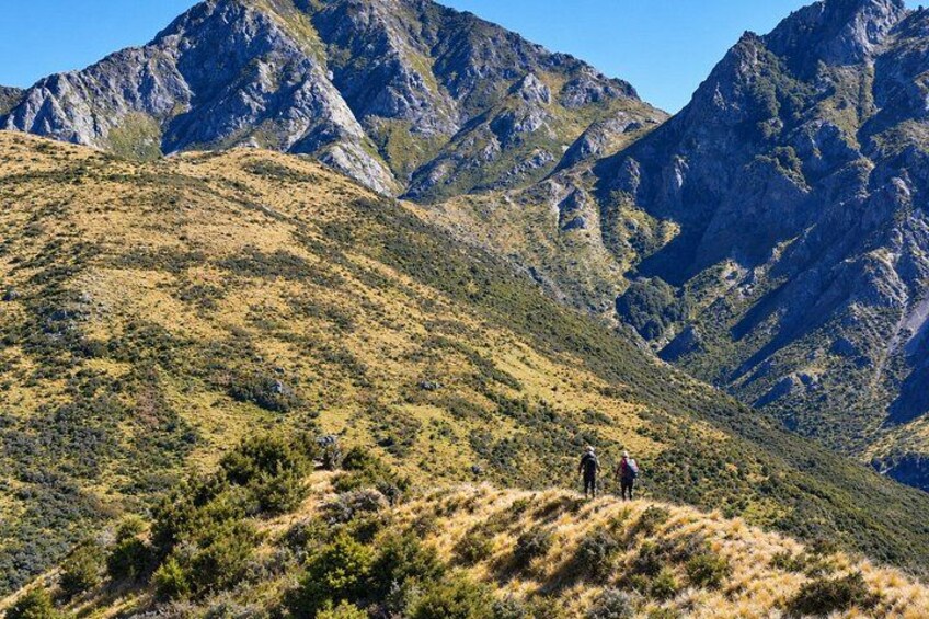A mountainous landscape with hikers on a trail. 1