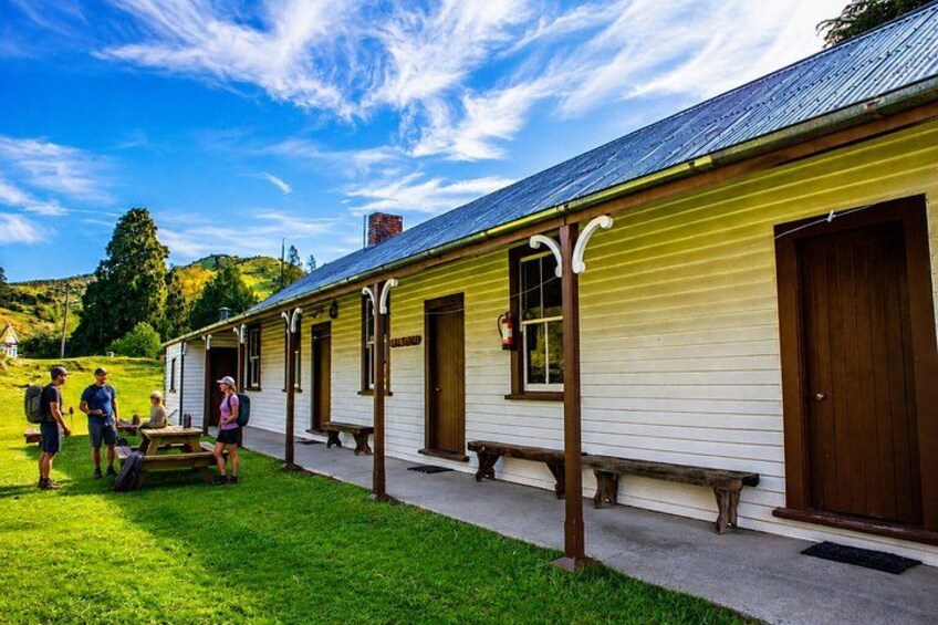 A yellow building with wooden doors and windows, surrounded by a grassy area. 2
