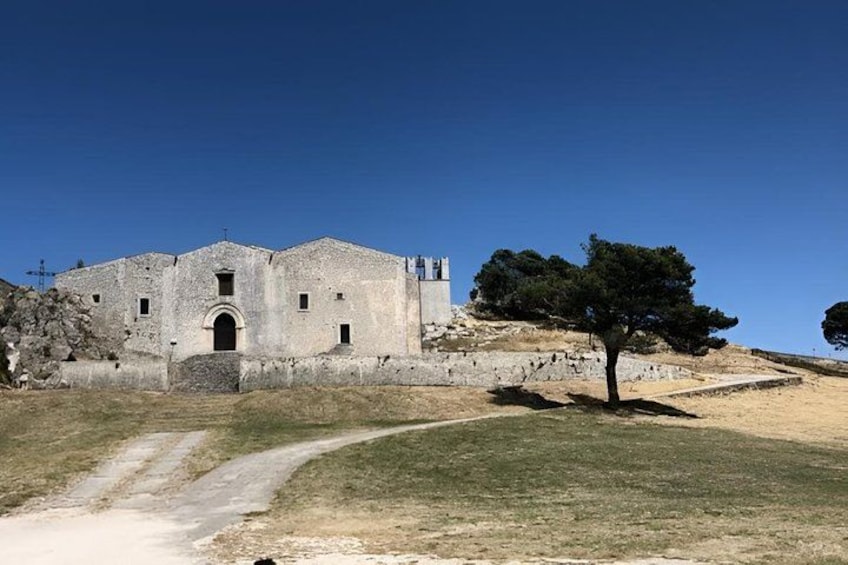 A historical building with a stone facade, a central archway, and a tree in the foreground. 5