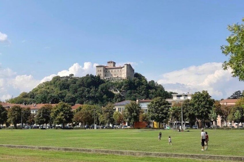 A castle on a hill with a grassy field and trees in the foreground. 5