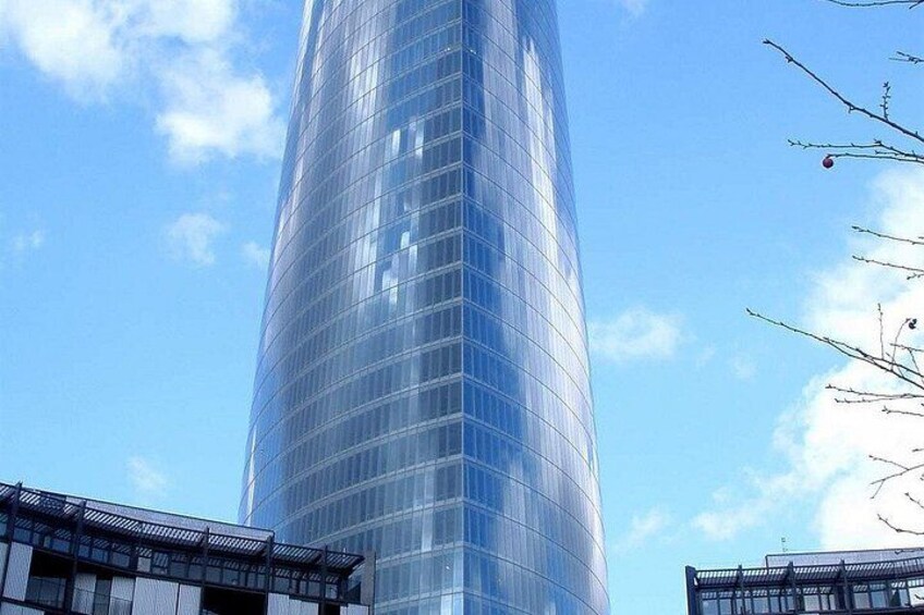 A tall glass skyscraper with a curved design, surrounded by other modern buildings. 3