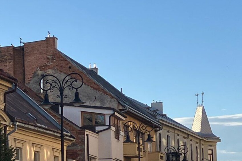 A row of historic buildings with ornate ironwork, a church steeple, and a clear blue sky. 4