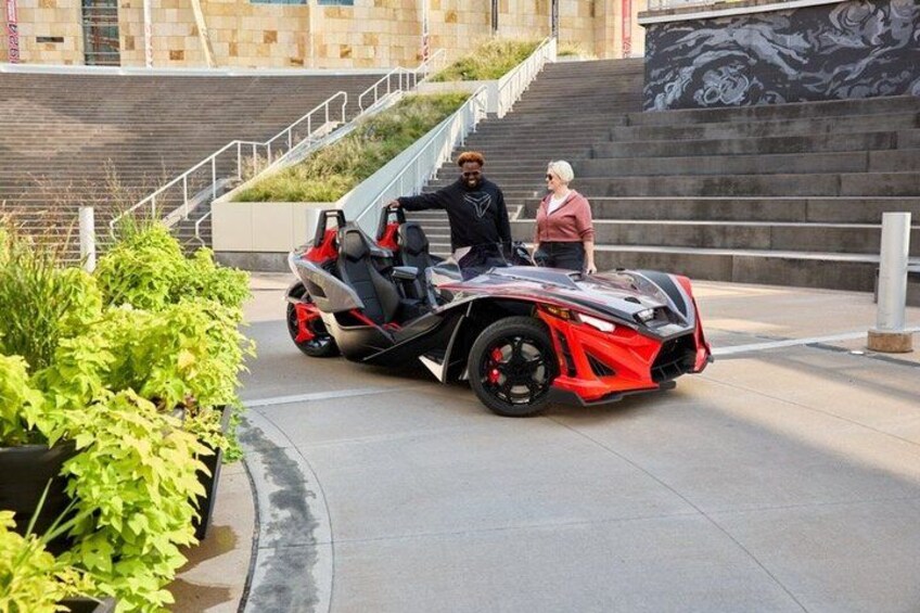 A red sports car parked on a paved area with stairs in the background. 3