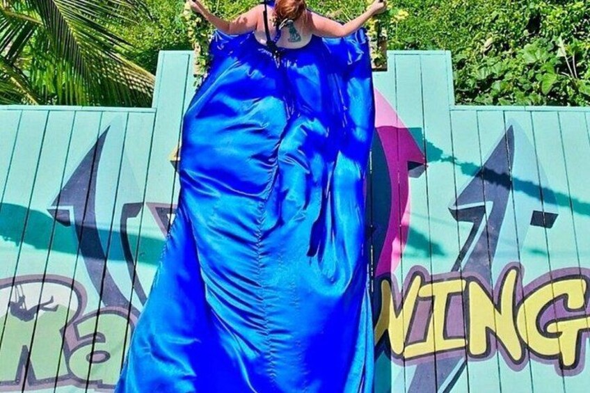 A person in a blue dress standing on a wooden fence with graffiti. 4