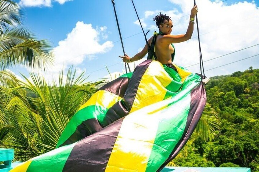 A person on a large inflatable structure with a flag, surrounded by palm trees and a clear sky. 1