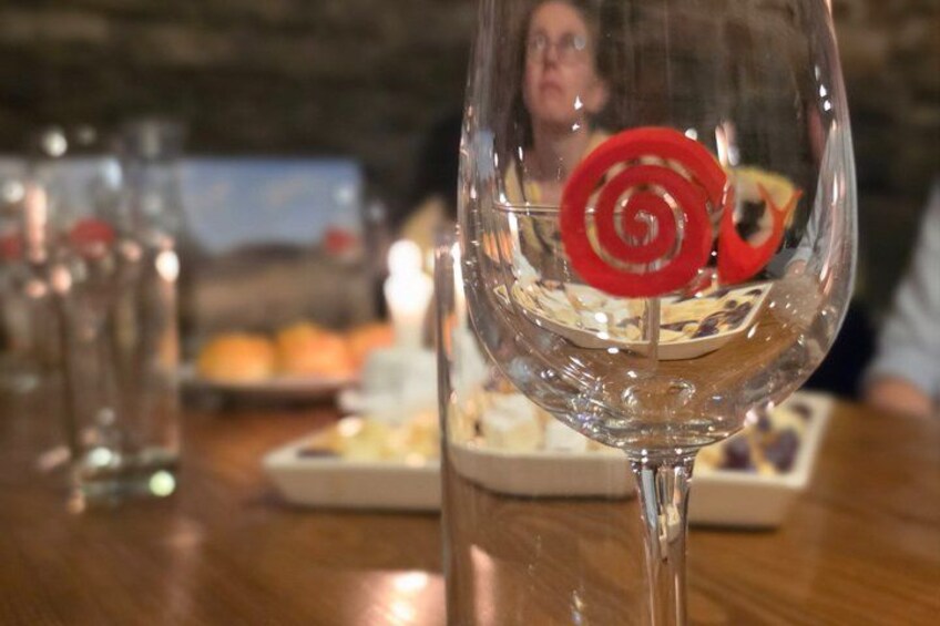 A glass with a red spiral decoration, a plate of food, and a blurred background with a person. 5