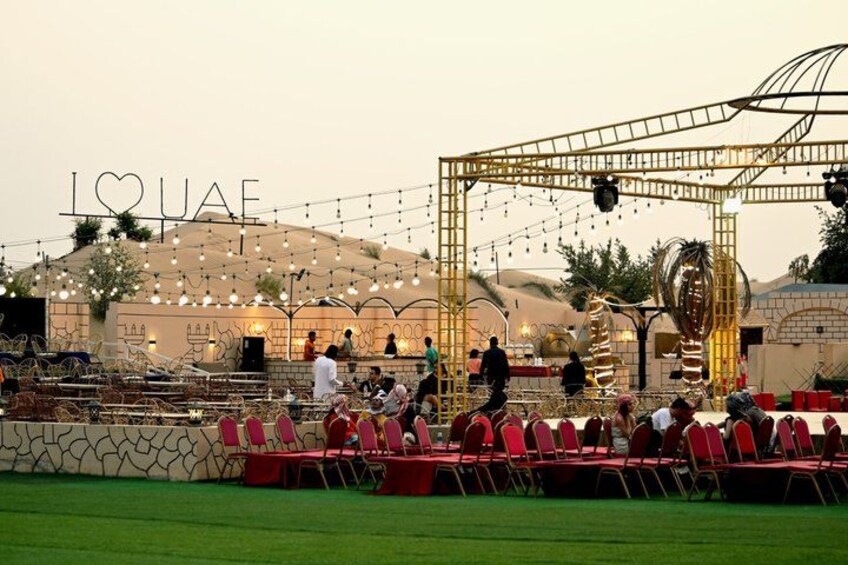 An outdoor event with a stage, chairs, and a backdrop with the word 'LOUAE'. 4