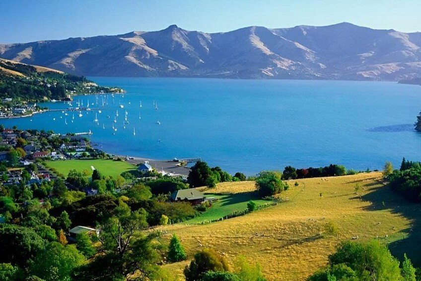 A coastal town with a marina, mountains in the background, and a mix of green fields and buildings. 5
