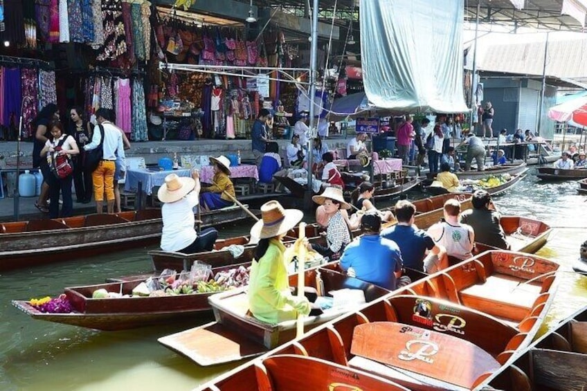 A crowded canal with people in boats, surrounded by market stalls and shops. 3