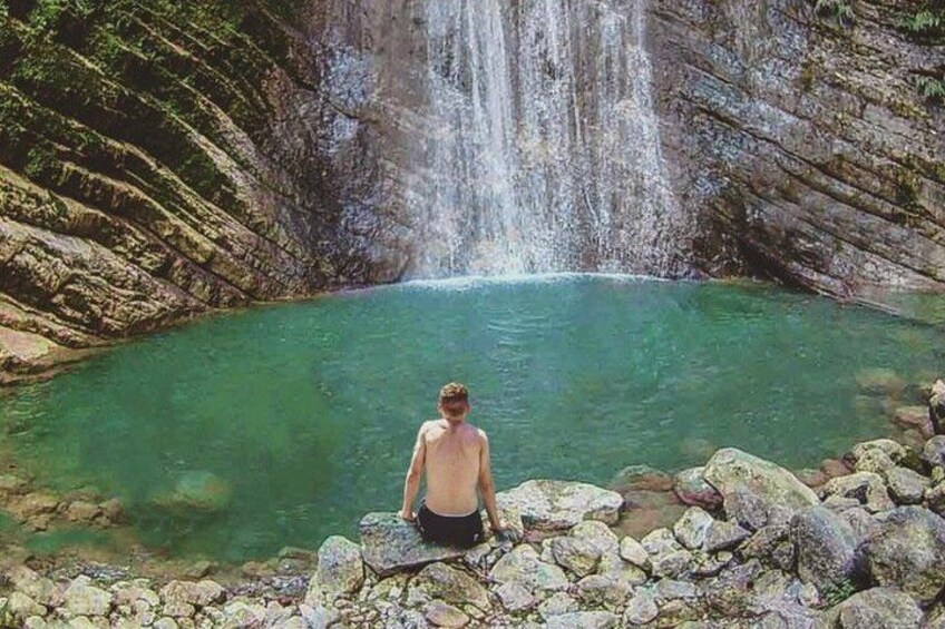 A person standing by a waterfall in a natural setting. 5