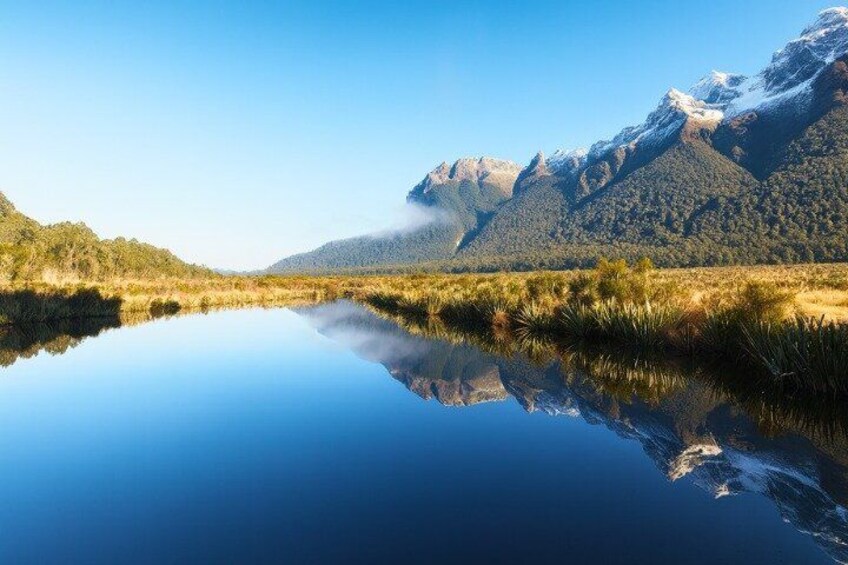 A calm lake reflecting mountains and clear sky. 4