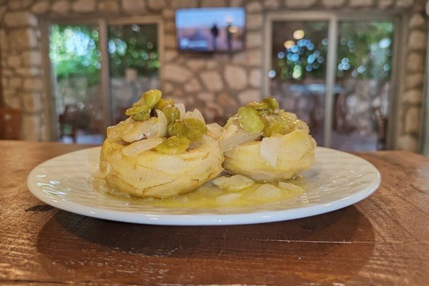 A plate of stuffed cabbage rolls with a side of sauce, placed on a wooden table in a restaurant. 3