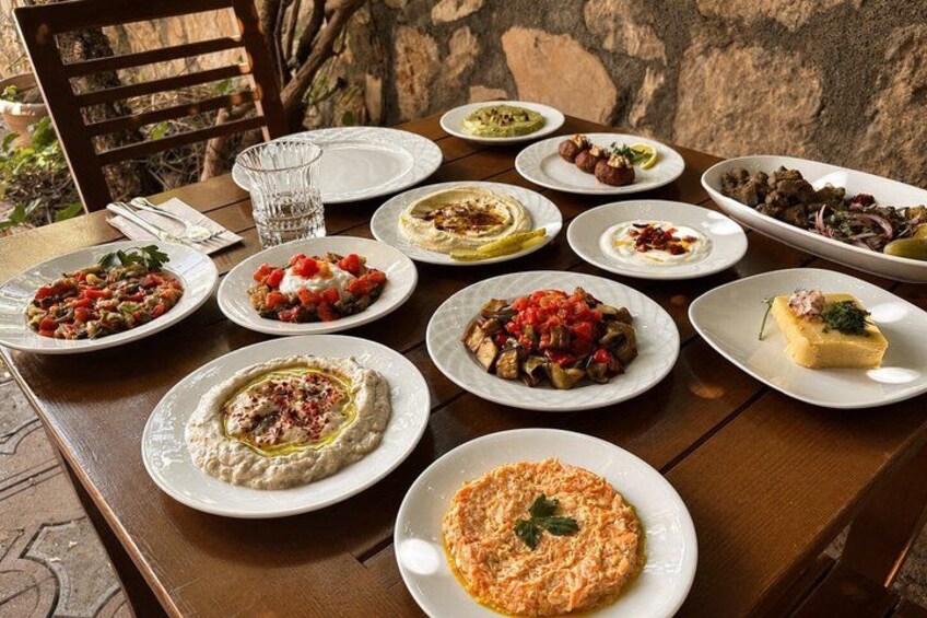 A wooden table with various dishes, including hummus, salads, and a dessert. 2