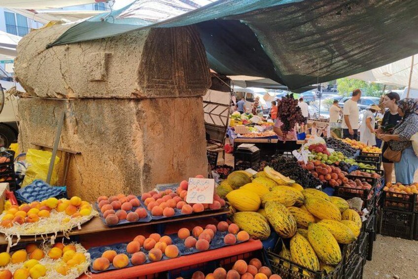 A market stall with various fruits and vegetables, including oranges, peaches, and melons. 1