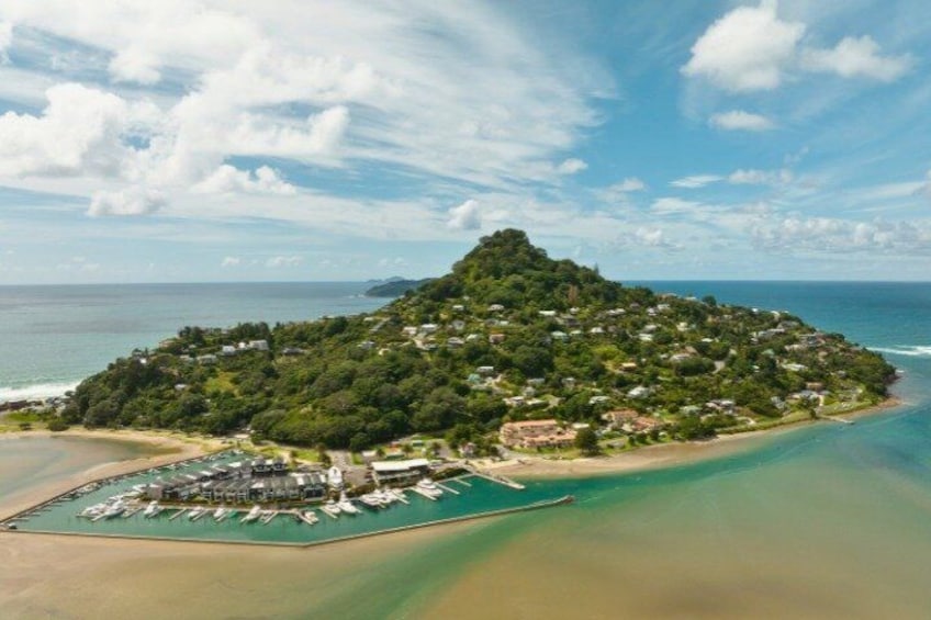 An island with a marina, lush greenery, and a clear blue sky. 1