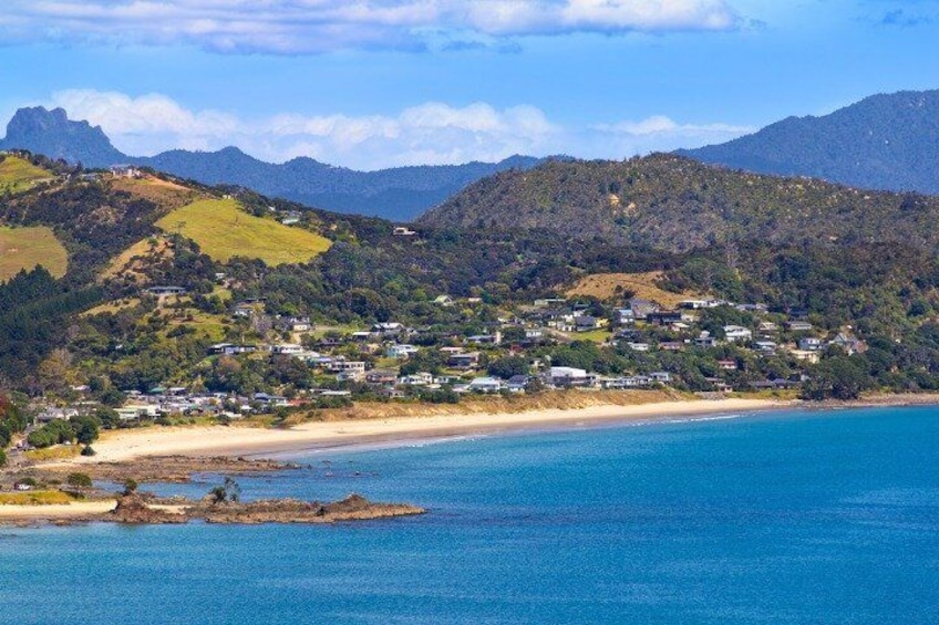 A coastal town with a beach, houses, and mountains in the background. 5