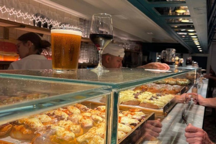 A bakery counter with pastries and a glass of beer. 4