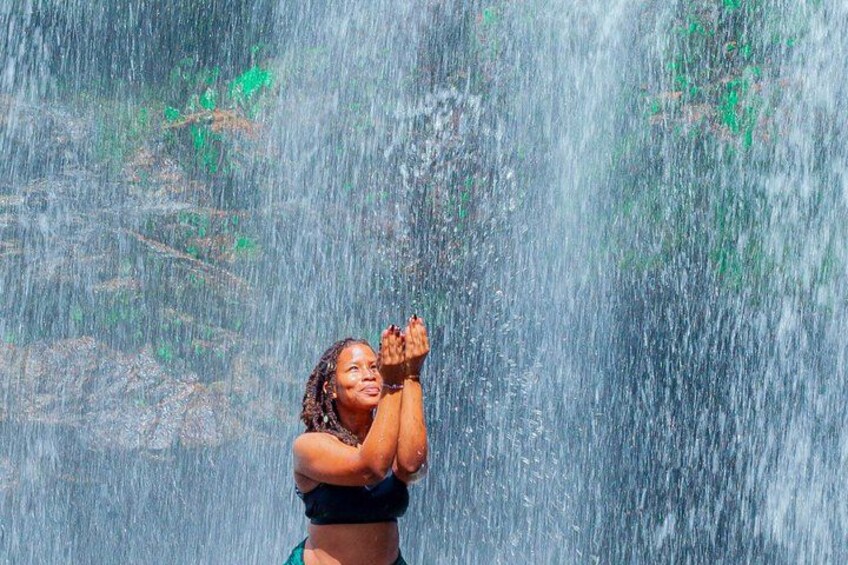 A person in a swimsuit standing in front of a waterfall. 5