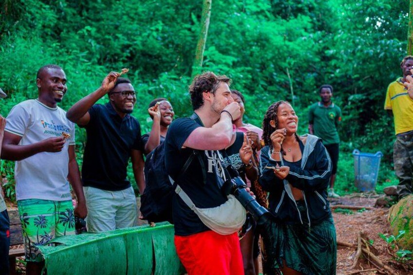 A group of people in a forested area, some holding food. 2