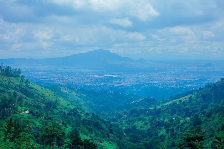 A valley with a cityscape in the distance, surrounded by lush green hills. 1