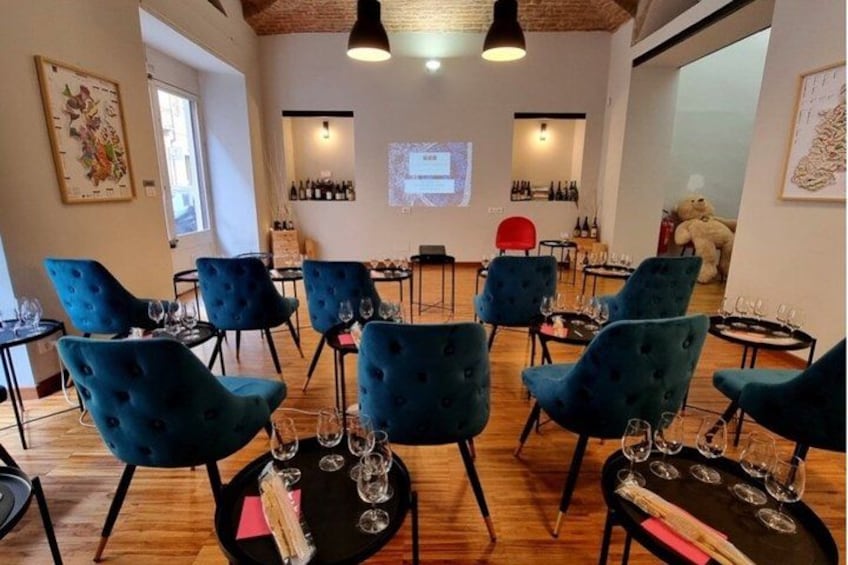 A room with blue chairs and tables, each with wine glasses and bottles. 3