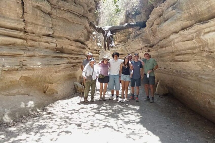A group of people standing in a narrow canyon with layered rock formations. 2
