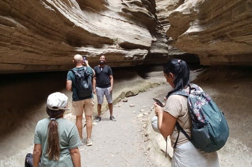 A group of people standing in a narrow canyon with rocky walls. 5