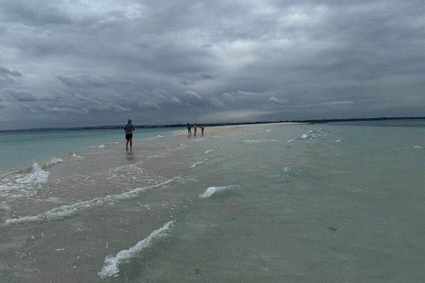 A beach with people walking along the shore under a cloudy sky. 3