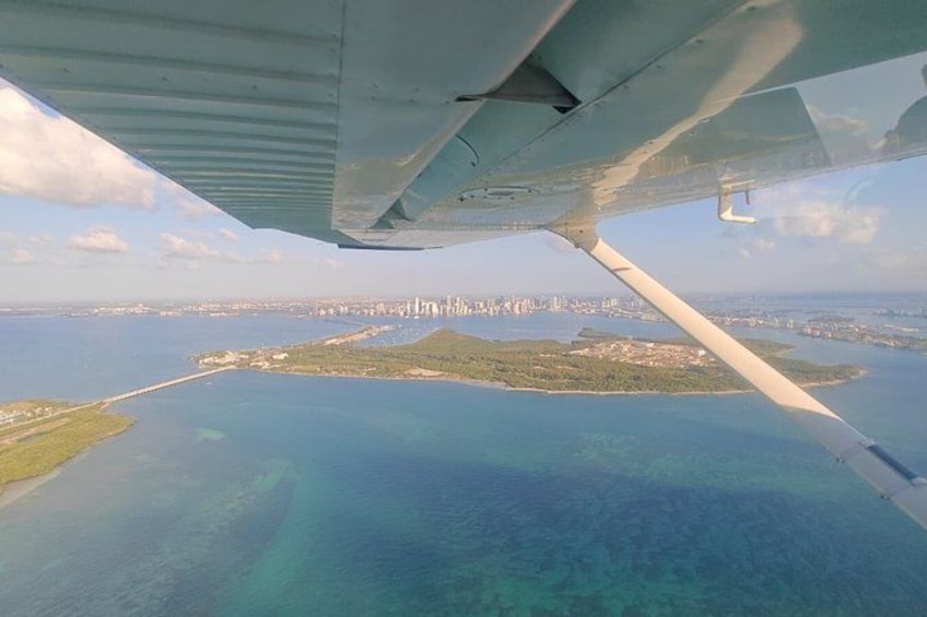 An airplane wing, a coastal cityscape, and a body of water. 3