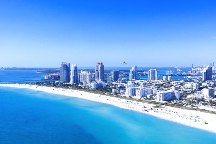 A coastal cityscape with a beach, high-rise buildings, and a clear blue sky. 5