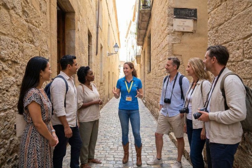 A group of people in a narrow street with stone walls, a sign reading 'Chambers,' and a person wearing a blue shirt and a lanyard. 5