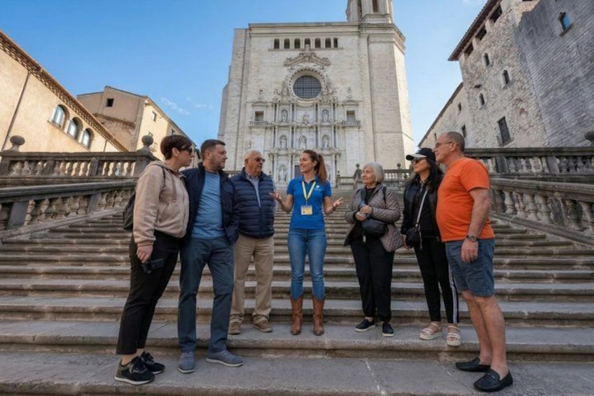 A group of people standing on steps in front of a large, ornate building with a clock tower. 1