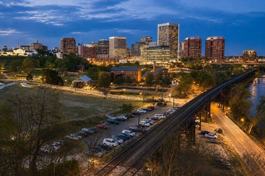A city skyline at dusk with a river, a bridge, and a parking lot. 4