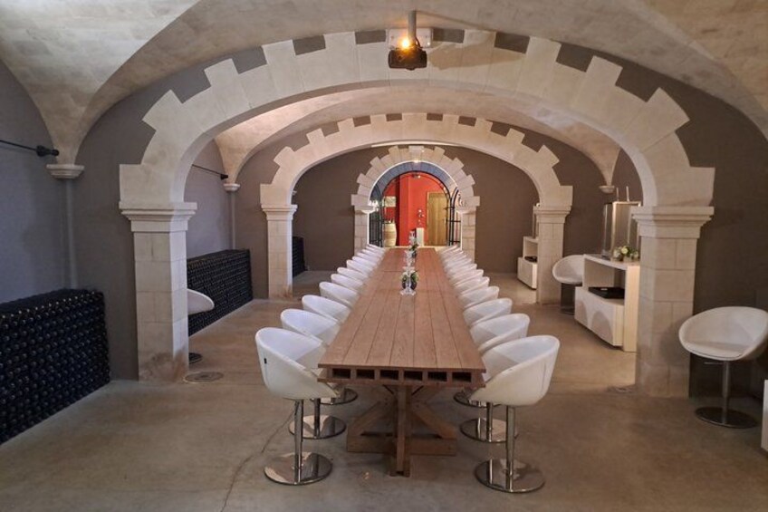 A long wooden table with white chairs in a room with arched ceilings and stone walls. 3