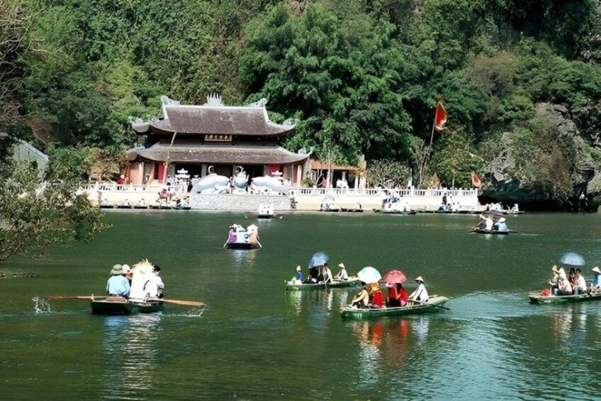 A traditional Chinese building by a lake with people on boats. 1