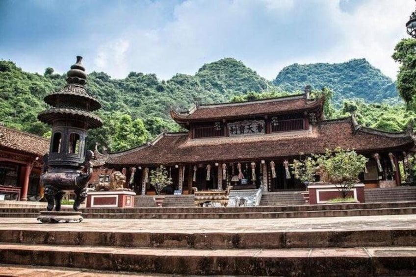 A traditional Chinese temple with a pagoda, surrounded by lush greenery and mountains. 5