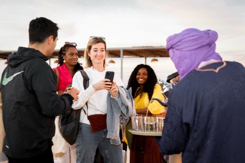 A group of people standing around a table with drinks, engaged in conversation. 3