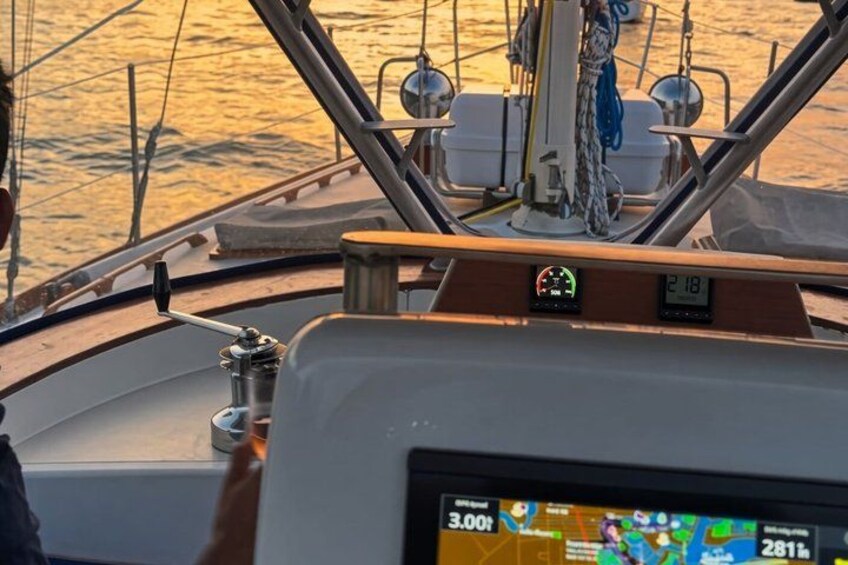 A boat's control panel with a digital display, a steering wheel, and a view of the water. 5