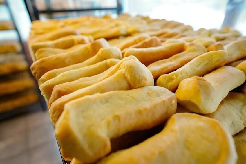 A display of golden-brown baked goods, likely bread or pastries, arranged in rows on a counter. 2